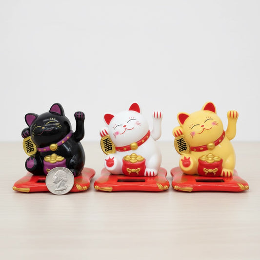 Collection of black, white, and yellow kawaii lucky cat fortune cat Chinese statues with size comparison to quarter coin